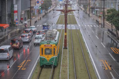 Çağdaş bir tramvay yağmurlu şehirlerde yeşil yollar boyunca seyahat ediyor.,