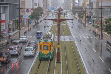 Çağdaş bir tramvay yağmurlu şehirlerde yeşil yollar boyunca seyahat ediyor.,