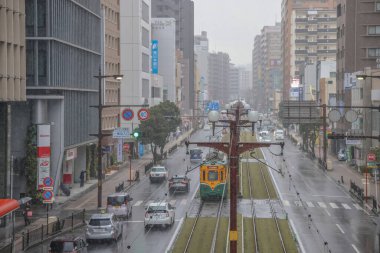 Çağdaş bir tramvay yağmurlu şehirlerde yeşil yollar boyunca seyahat ediyor.,