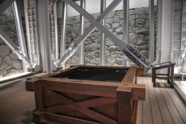 24 Mart 2025 Yapısal kirişler ve ahşap mobilyalar taş duvarlı iyi aydınlatılmış bir alanda sergileniyor