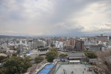 24 Mart 2025 Yüksek binalar, yeşil alanlar içeren hareketli bir şehir manzarası,