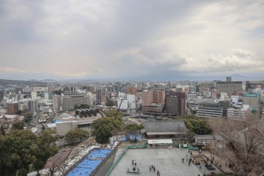 24 Mart 2025 Yüksek binalar, yeşil alanlar içeren hareketli bir şehir manzarası,