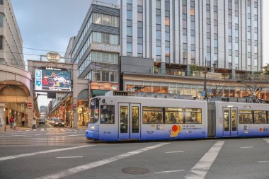 24 Mart 2025 Şehir tramvayı modern binalarla çevrili kalabalık bir sokaktan geçiyor.