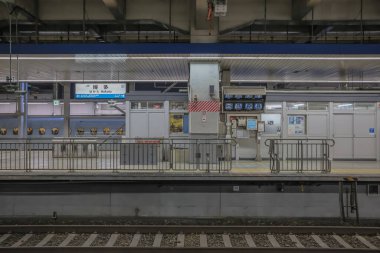 Aydınlatılmış tren istasyonu platformu tabelaları, rayları, kapıları