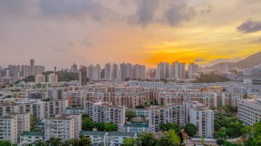 Şehir silueti yüksek binalar ve canlı bir günbatımı sergiliyor.