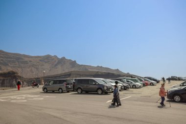 Açık mavi gökyüzünün altındaki kayalık dağların yakınındaki otoparkta.