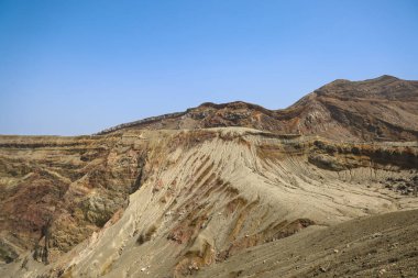 Uzak küçük kulübelerin olduğu çorak çöl manzarası, açık mavi bir gökyüzü.