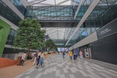 Geniş bir yaya yolu modern cam binalar ve ağaçlarla kaplı.,