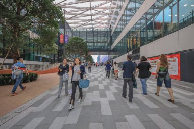 Geniş bir yaya yolu modern cam binalar ve ağaçlarla kaplı.,