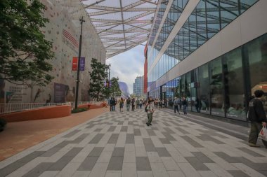 Geniş bir yaya yolu modern cam binalar ve ağaçlarla kaplı.,
