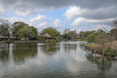 24 Mart 2025 Etrafı yeşil manzaralarla çevrili sakin göl, bahçe ağaçları,