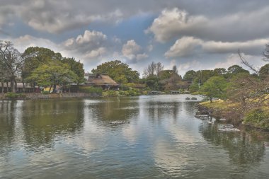 24 Mart 2025 Etrafı yeşil manzaralarla çevrili sakin göl, bahçe ağaçları,