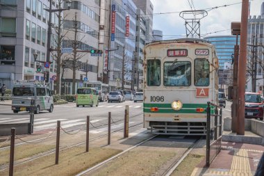 24 Mart 2025 Şehir tramvayı modern binalarla çevrili kalabalık bir sokaktan geçiyor.