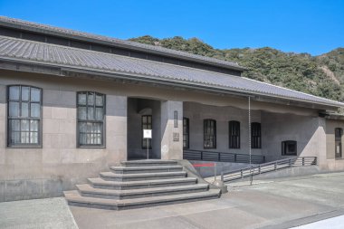 23 Mart 2025 Büyük pencereleri ve basamakları olan tarihi bir taş binanın dış görünüşü,