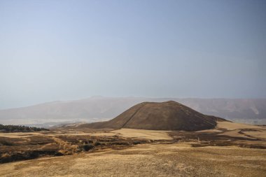 Açık arazilerle çevrili büyük kahverengi bir tepenin huzurlu manzarası.
