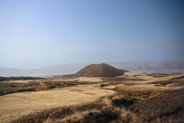 Açık arazilerle çevrili büyük kahverengi bir tepenin huzurlu manzarası.