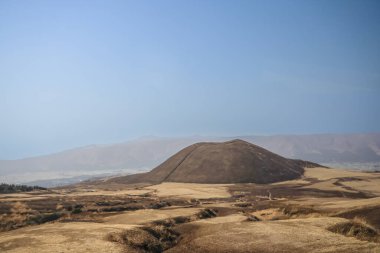Açık arazilerle çevrili büyük kahverengi bir tepenin huzurlu manzarası.