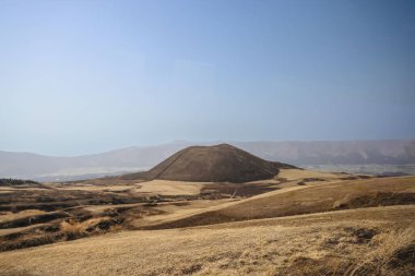 Açık arazilerle çevrili büyük kahverengi bir tepenin huzurlu manzarası.
