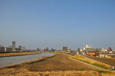 Çağdaş binalarla çevrili akan bir nehrin yer aldığı şehir manzarası