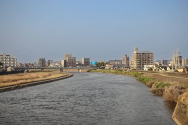 Çağdaş binalarla çevrili akan bir nehrin yer aldığı şehir manzarası