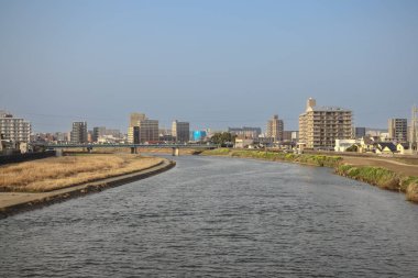 Çağdaş binalarla çevrili akan bir nehrin yer aldığı şehir manzarası