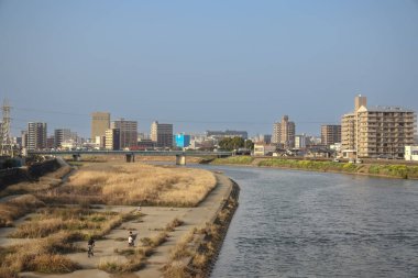 Çağdaş binalarla çevrili akan bir nehrin yer aldığı şehir manzarası