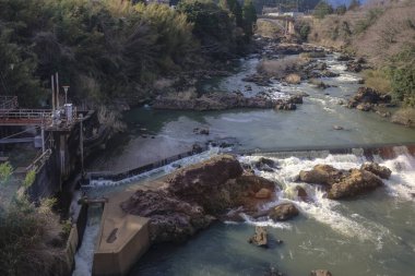 Huzurlu bir nehir yavaşça akar ve çağlayan küçük şelaleler oluşturur.