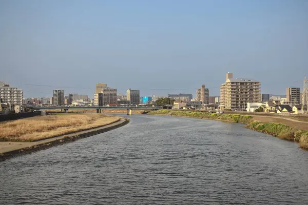 Çağdaş binalarla çevrili akan bir nehrin yer aldığı şehir manzarası