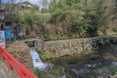 Huzurlu bir gölet, canlı kırmızı bir köprü ve çevresini saran doğa huzur için mükemmel.