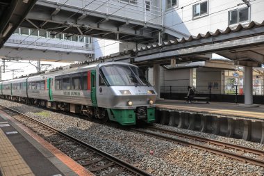 Çağdaş tren etkileyici bir şehir üst geçidinin altındaki istasyon platformunda bekliyor..