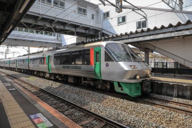 Çağdaş tren etkileyici bir şehir üst geçidinin altındaki istasyon platformunda bekliyor..