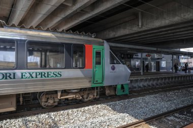 Çağdaş tren etkileyici bir şehir üst geçidinin altındaki istasyon platformunda bekliyor..