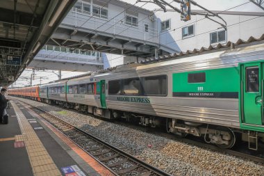 Çağdaş tren etkileyici bir şehir üst geçidinin altındaki istasyon platformunda bekliyor..