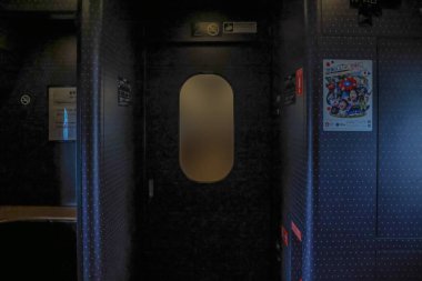 Sessiz ve loş ışıklı tren koridoru, donuk cam kapılı, hafifçe aydınlatılmış.