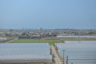 sergilenen yeşil tarım alanları, beyaz seralar, geleneksel evler,