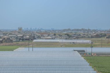 sergilenen yeşil tarım alanları, beyaz seralar, geleneksel evler,