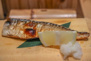 Taze limonla birlikte bambu yaprağında dinlenen lezzetli ızgara uskumru.