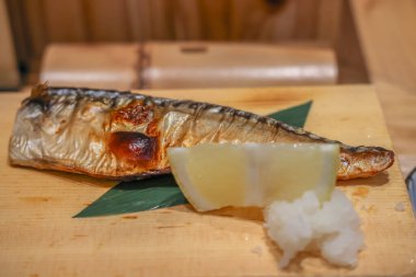 Taze limonla birlikte bambu yaprağında dinlenen lezzetli ızgara uskumru.