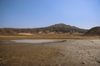 Ön planda küçük bir su birikintisi olan kuru, düz bir arazi.