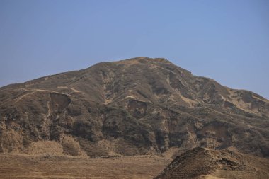 Engebeli yamaçlara ve seyrek bitkilere sahip çorak bir dağ arazisi.
