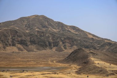 Engebeli yamaçlara ve seyrek bitkilere sahip çorak bir dağ arazisi.