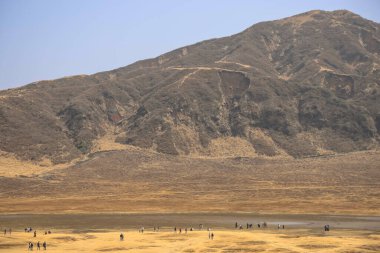 Engebeli yamaçlara ve seyrek bitkilere sahip çorak bir dağ arazisi.