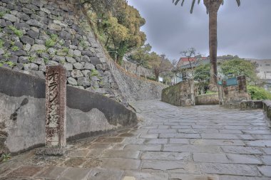 Etrafı taştan bir duvarla çevrili bir yol.