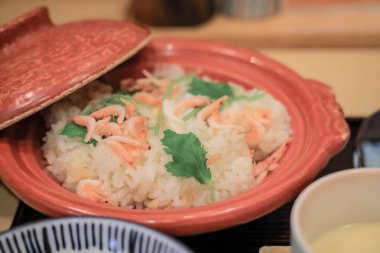 İçinde küçük karides ve taze pirinç bulunan süslü bir kase.