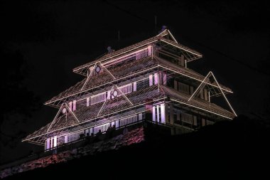 Pembe ışıklar geleneksel bir Japon kalesini aydınlatıyor.,