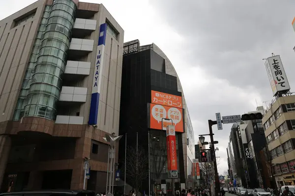 Ticari tabela ve bulutlu gökyüzü altında hareketli yaya etkinliği.