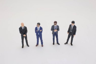 Takım elbiseli dört minyatür iş adamı bir arada duruyor.