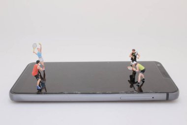 Akıllı telefon ekranındaki küçük tenis oyuncularının eşsiz kompozisyonu