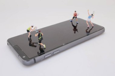 Akıllı telefon ekranındaki küçük tenis oyuncularının eşsiz kompozisyonu