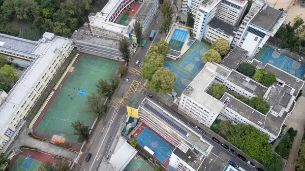 Spor sahaları, yollar ve ağaçlarla çevrili bir şehir okulunun genel bakış açısı.